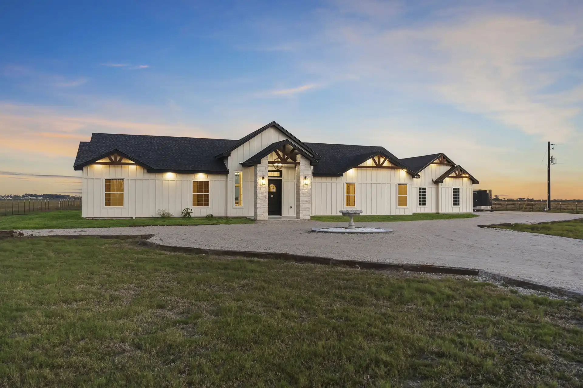 Custom farmhouse at dusk with warmly lit windows, built by Go To Guys RGV in La Feria, TX