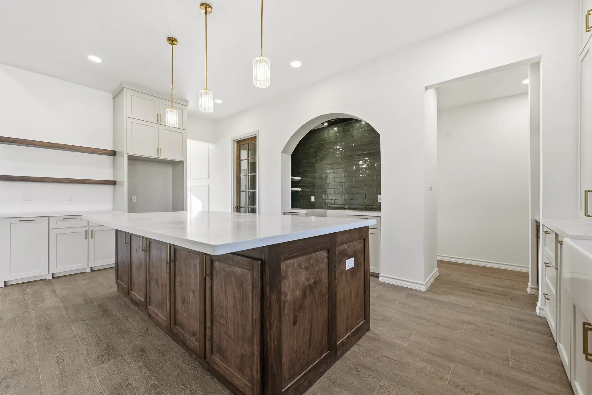 Custom kitchen island with an arched tiled niche and brass pendants, built by Go To Guys RGV