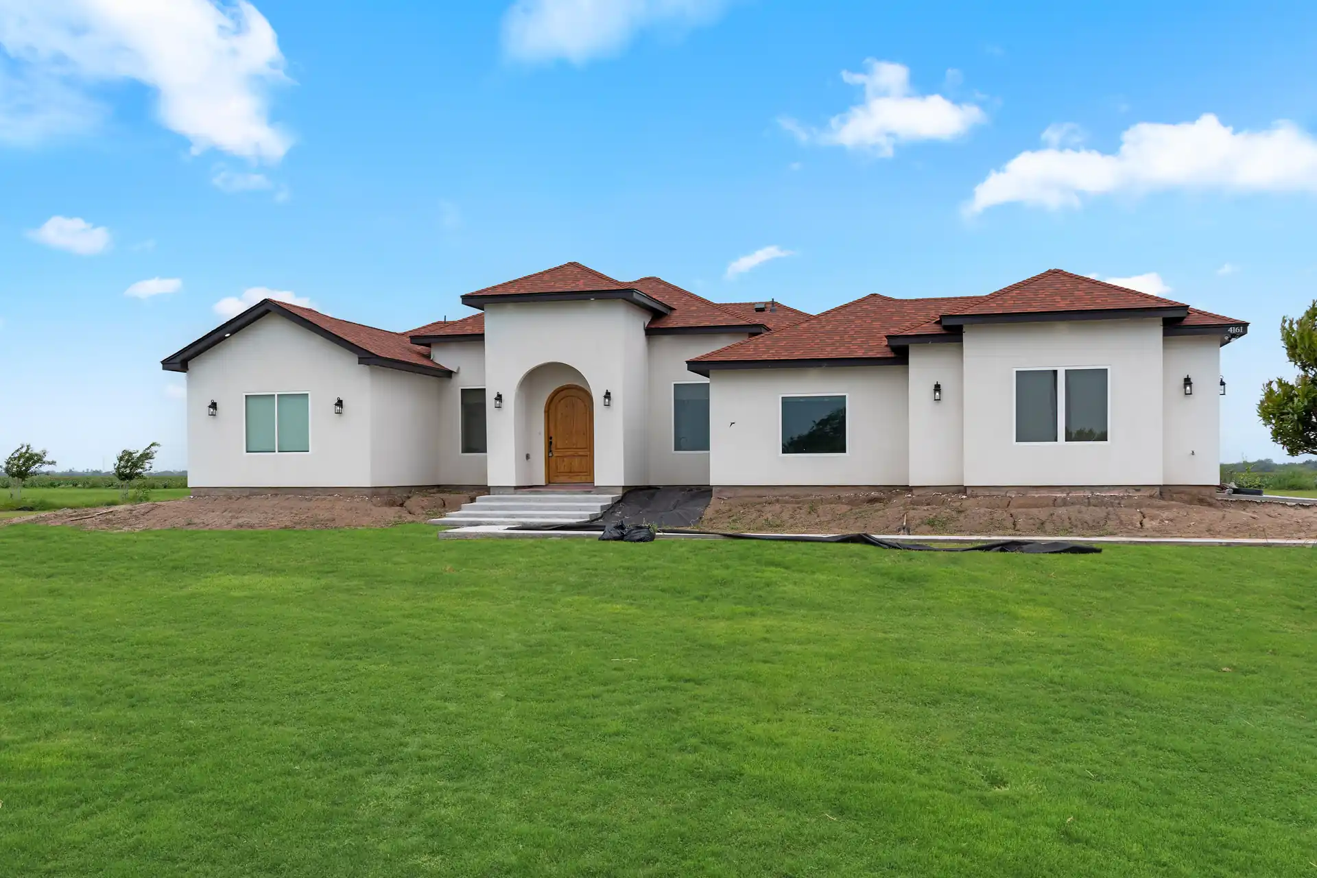 White stucco custom home with a tile roof and arched entry, built by Go To Guys RGV in Harlingen, TX